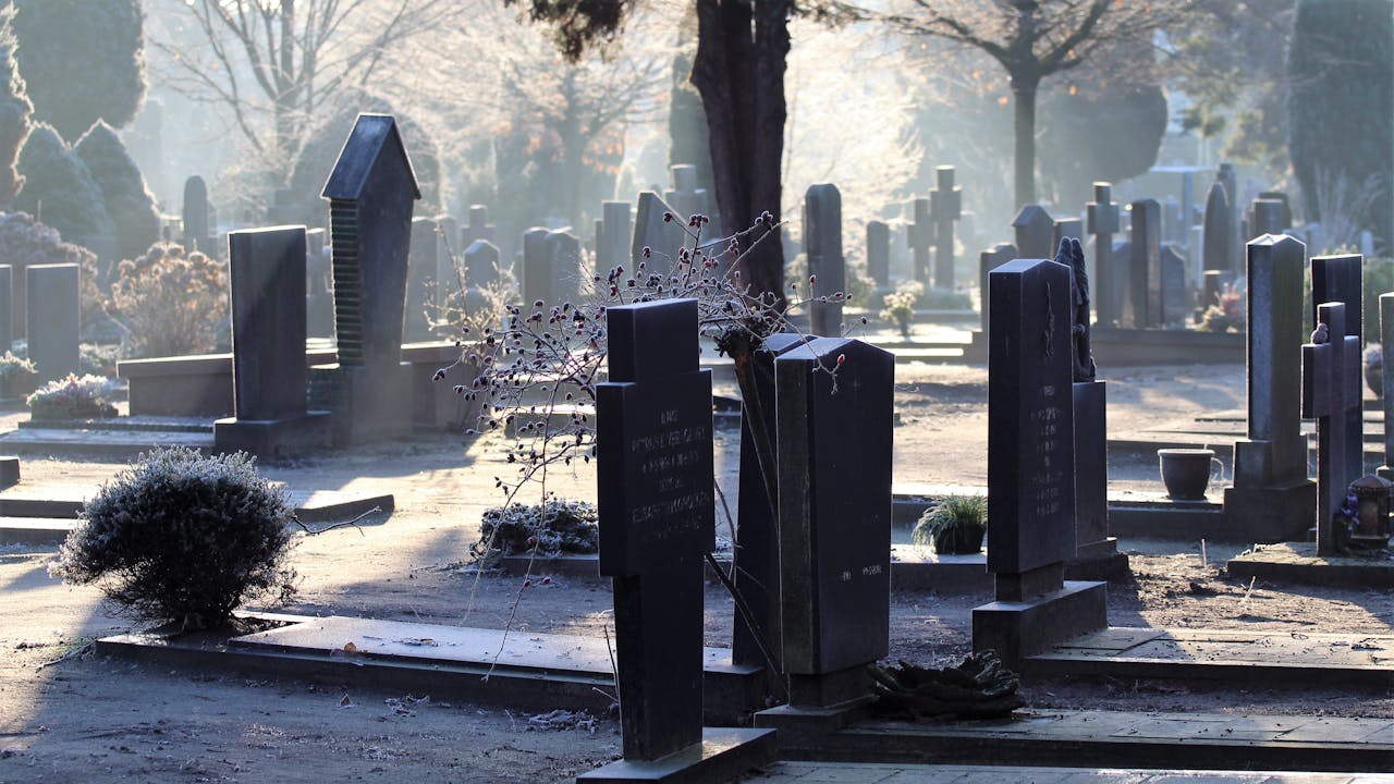 A peaceful cemetery scene captured at sunrise, with mist and tombstones creating a tranquil atmosphere.