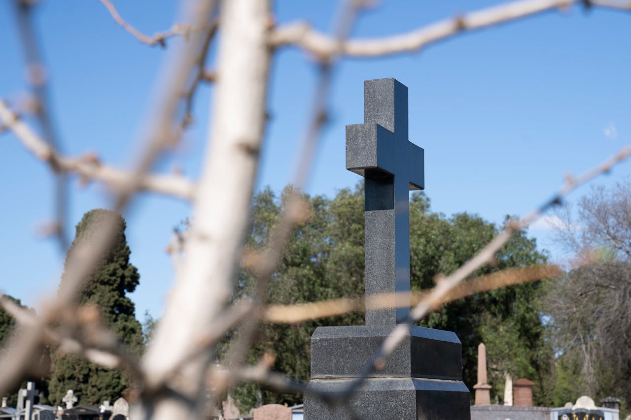Peaceful cemetery with a prominent cross against a clear blue sky in Melbourne.