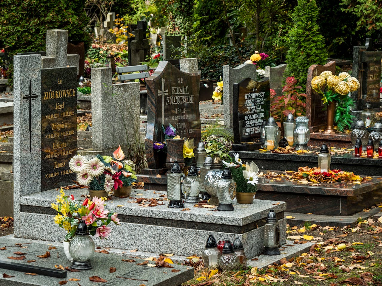Serene cemetery scene featuring beautifully decorated graves with colorful flowers and lanterns.