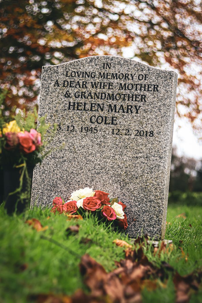 Gravestone of Helen Mary Cole with flowers in an English cemetery during autumn.