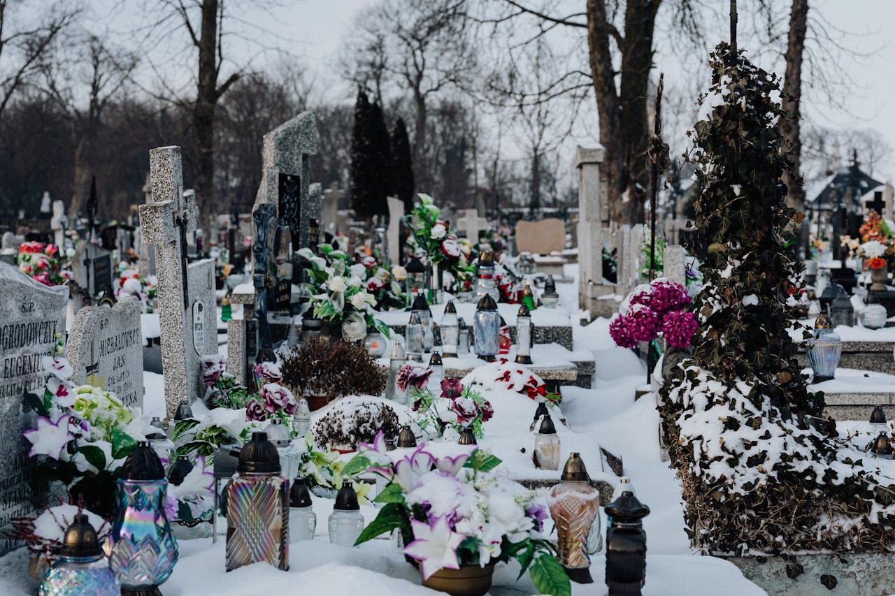 Snow-covered cemetery with colorful flowers and gravestones, evoking a serene winter atmosphere.