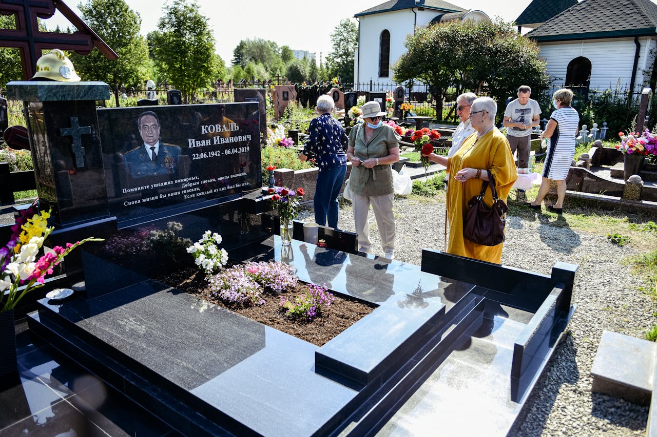 Visitors at a cemetery memorial site, paying respects to the deceased.