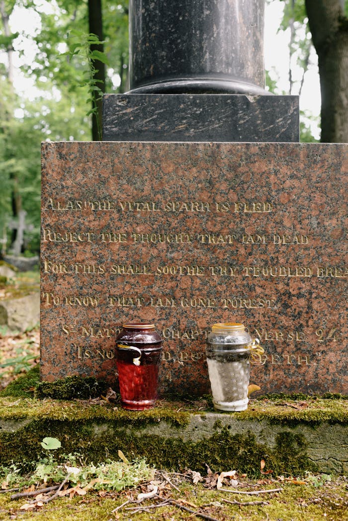 Close-up of a granite tombstone with candles in a serene cemetery setting.